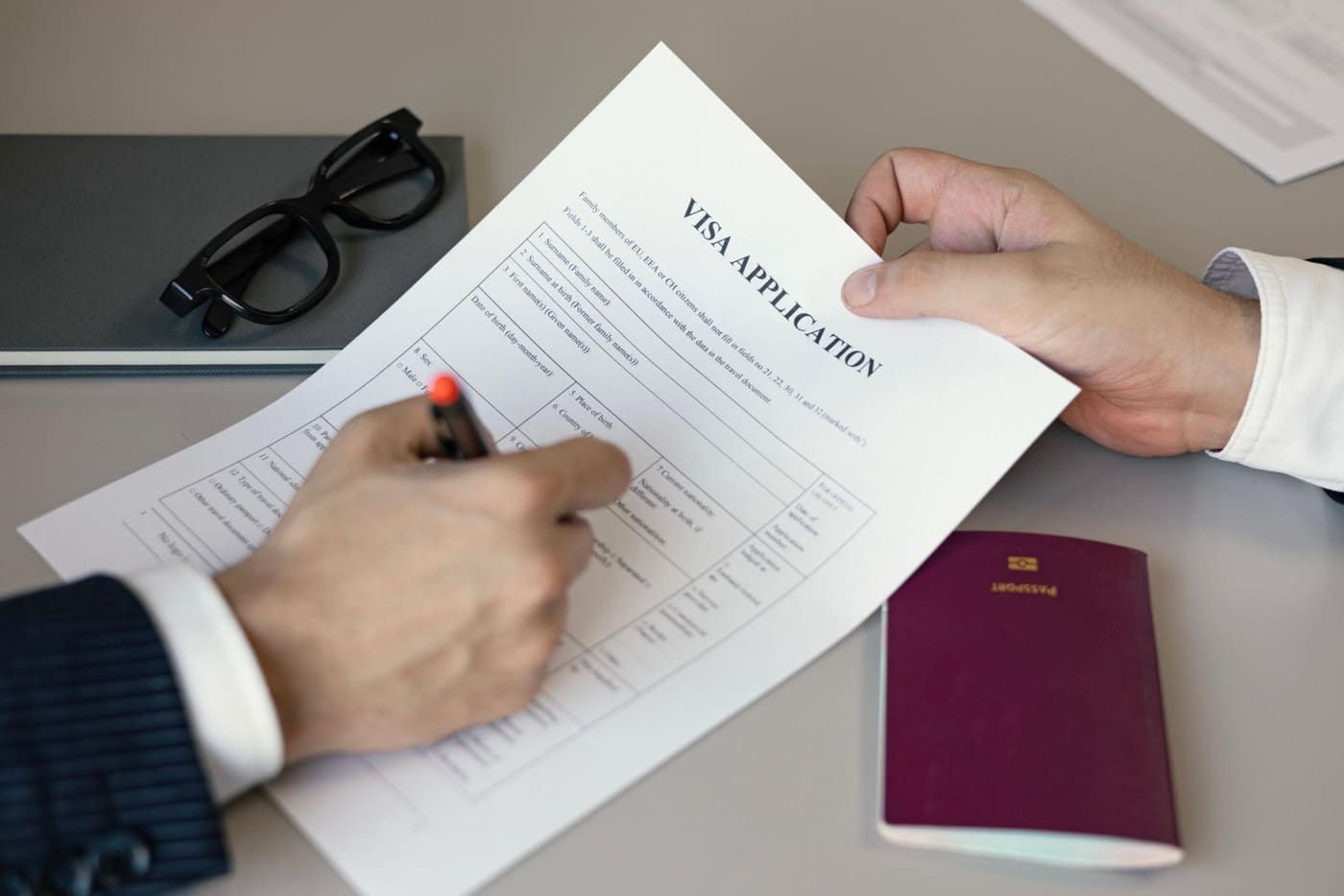 A visa application form and passport being reviewed and signed